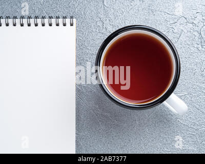 metal mug with tea, empty a blank sheet of Notepad on the spiral on a gray metallic background Stock Photo