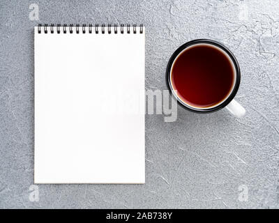 metal mug with tea, empty a blank sheet of Notepad on the spiral on a gray metallic background Stock Photo