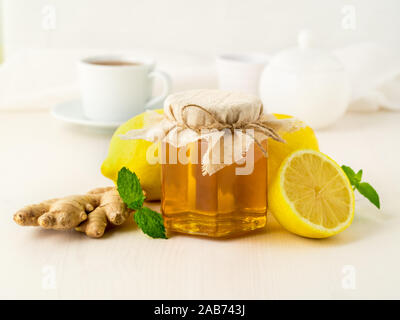 Popular ways to treat a cold - a jar of honey, ginger, mint, lemons on white background, side view Stock Photo