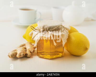 Popular ways to treat a cold - a jar of honey, ginger, lemons on white background, side view Stock Photo