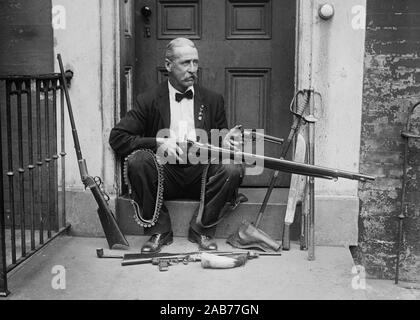 Man sitting on porch with multiple guns and rifles ca. 1927 Stock Photo
