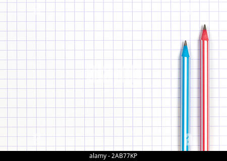 Two striped pencils on white squared paper notebook background. Top view Stock Photo