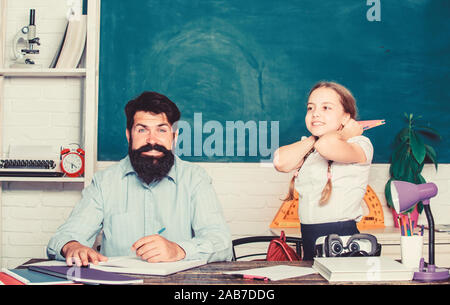 It is unbelievable. daughter study with father. Teachers day. knowledge day. Home schooling. back to school. Private teaching. private lesson. small girl child with bearded teacher man in classroom. Stock Photo