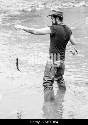 Fishing masculine hobby. Brutal man wear rubber boots stand in