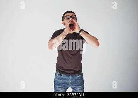 Emotional man in casual clothes loudly screams as if someone is calling. His feelings are overwhelming Stock Photo