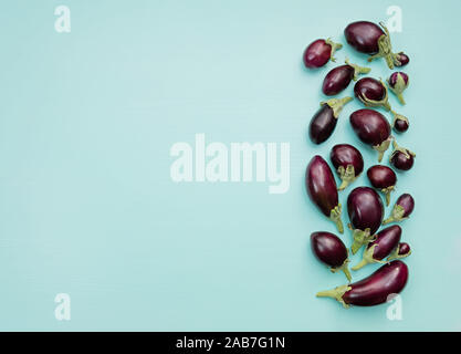 Eggplants of different sizes on a wooden background with mint color. Flat lay. Top view. Copy space. Stock Photo
