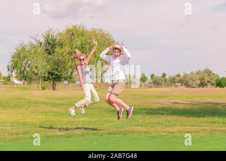 young couple jumping in a green field Stock Photo