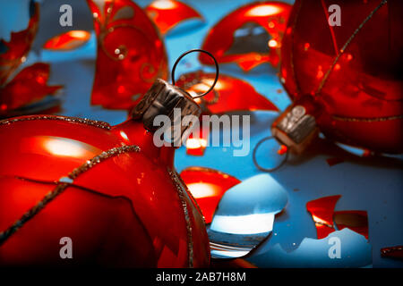 Bright orange, glass Christmas baubles broken, scattered fragments on a blue background Stock Photo