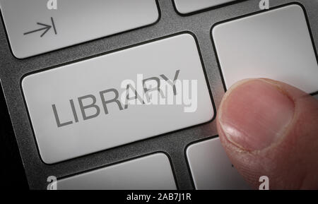A man pressing a key on a computer keyboard with the word library. Online library concept image. Stock Photo