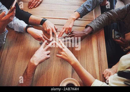Close up top view of young people putting their hands together. Friends Doing a Star Shape with fingers showing unity and teamwork Stock Photo