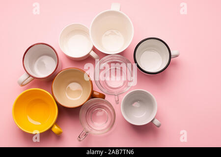 Empty cups and glasses for various drinks stand on a pink table. Flat layout top view. Drinks concept. Copy space. Horizontal frame Stock Photo