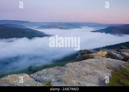 Dawn light breaks above the Peak District hills with a cloud inversion covering the Ladybower Reservoir, Peak District, Derbyshire, UK Stock Photo