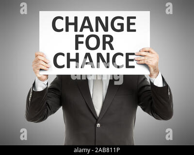 Ein Geschaeftsmann, der ein Schild mit den Worten 'Change for Chance' haelt Stock Photo