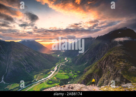 Elevated view of man standing on Romsdalseggen ridge admiring Rauma valley during sunset, Andalsnes, More og Romsdal, Norway, Scandinavia, Europe Stock Photo