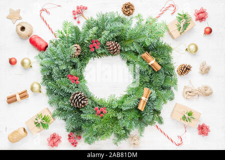 Creative layout handmade Christmas wreath and various objects, presents, labels, cinnamon sticks, pinecones on wooden table, top view, selective focus Stock Photo