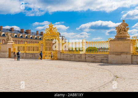 Great panoramic view of the shiny golden Royal Gate, an elaborate gold leaf gate, seen from inside the Cour Royale of the famous Palace of Versailles... Stock Photo