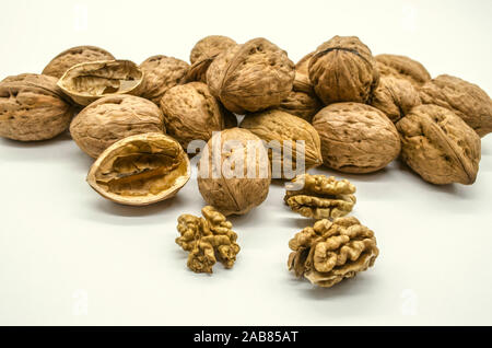 Groups of ripe walnut seeds in shells and peeled kernels with halves of nut shells on a white background Stock Photo
