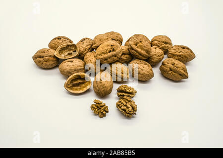 Peeled kernels with walnut shell halves with a bunch of ripe autumn walnut seeds in the shell on white background Stock Photo