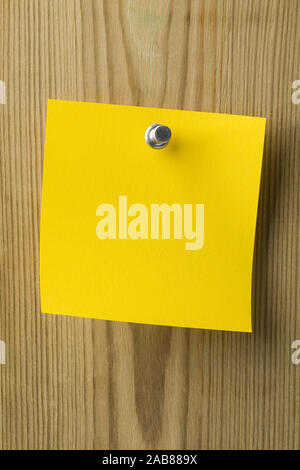 Empty yellow paper sticky note pinned to a wooden board Stock Photo