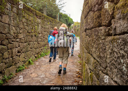 Group of friends walking with backpacks from back. Backpackers tourists walk along the walls of the ancient city. Adventure, travel, tourism, active Stock Photo