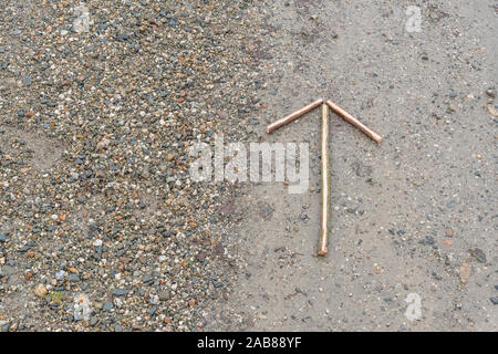 Survival skills concept. Signal arrow on gravel 'proceed this way' / 'proceeding in this direction' to show direction of movement or position. Stock Photo