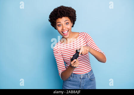 Photo of cheerful excited crazy consoller smiling toothily wearing jeans denim enjoying playing isolated blue pastel curly wavy color background Stock Photo