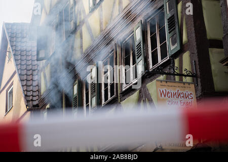 Neudenau, Germany. 26th Nov, 2019. Smoke rises from the burnt-out and smashed windows of a burning half-timbered house, while in the foreground there is barrier tape. Two of the three missing persons were found dead in the house. Credit: Tom Weller/dpa/Alamy Live News Stock Photo