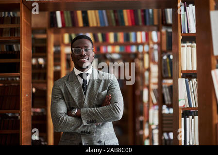 An African American man in a business suit standing in a library in the reading room. Stock Photo