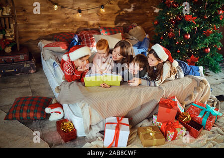 Woman with children reading book on bed with gifts Stock Photo
