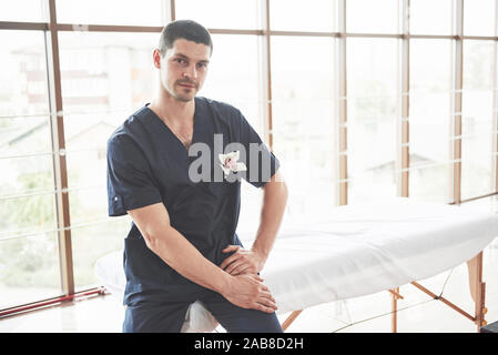 Portrait of young smiling man in uniforme near massage couches Stock Photo