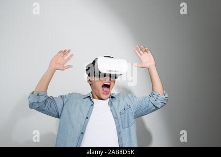 young happy and excited Asian man wearing virtual reality vr 360 vision goggles enjoying video game Stock Photo
