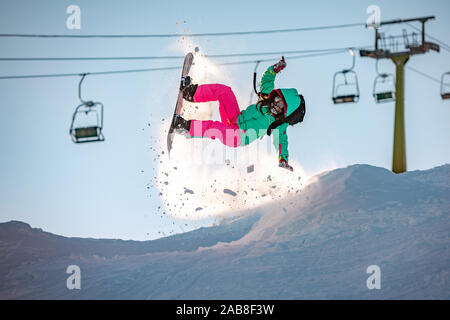 Girl snowboarder jumps from kicker, fails and falls on snowboard Stock Photo