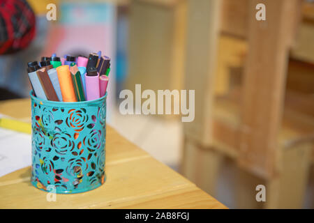 Box for pens and pencils . Colored pencils in a pencil case on the wooden table . Color pencils in aqua case . Stock Photo