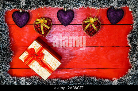 Christmas composition on red wooden board with Christmas garland and decorations. Creative composition with border and copy space, top view, flat lay. Stock Photo