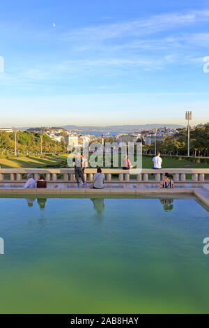 Tourists admiring the view down Eduardo VII Park, Parque Eduardo VII towards Marquês de Pombal and the distant Tagus River, Lisbon, Portugal. Stock Photo