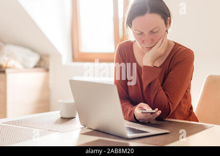Woman telecommuting in home office interior. Portrait of female freelancer using mobile phone, selective focus. Stock Photo
