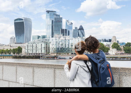 Two guys hold each other while watching the London skyline on a summer day Stock Photo