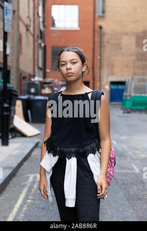 Portrait of a young girl in an alley full of garbage. Casual clothes. Urban context Stock Photo