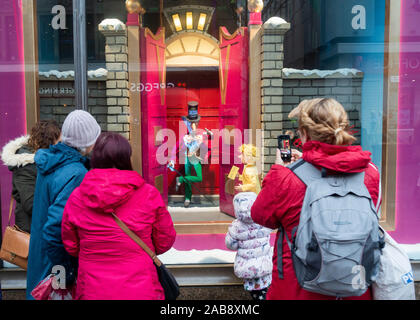 Newcastle upon Tyne, England, UK. 26th November, 2019. Weather: People admiring the Fenwick store Christmas window display in Newcastle city centre on a cold, grey, drizzly Tuesday in the north east of England. Credit: Alan Dawson /Alamy Live News Stock Photo