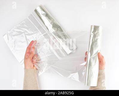 Plastic food wrap for baking products in the oven in women's hand, view from the top, white background.