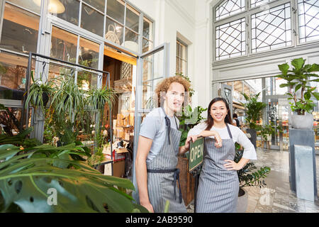 Two florists as a team with open sign in front of garden center as a business Stock Photo