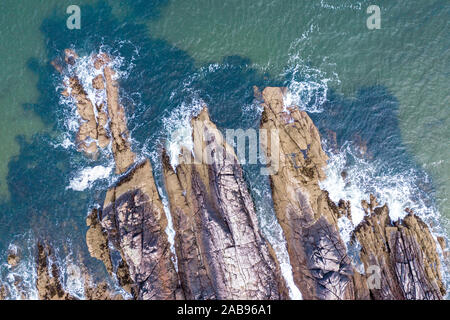 Blue ocean waves crashing against rocky cliffs  - aerial top down view. Firemore Beach in the Northwest Highlands of Scotland Stock Photo