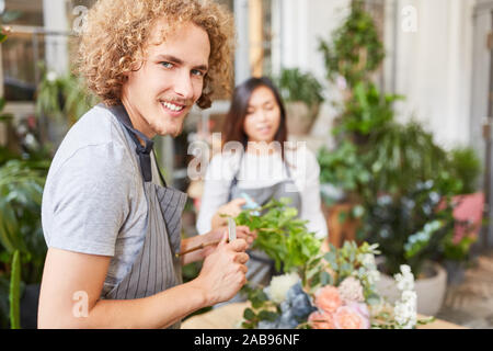Young man as florist in training learns to tie bouquet Stock Photo