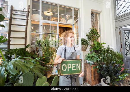 Florist as a clerk or boss with open sign in front of florist Stock Photo