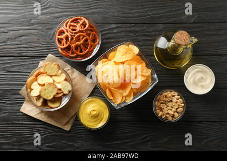 Beer snacks, potato chips, beer nuts, sauces, olive oil on wooden background, space for text. Top view Stock Photo