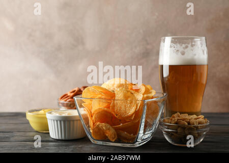 Beer snacks, glass of beer, potato chips, beer nuts, sauces, glass of beer on wooden background, space for text Stock Photo