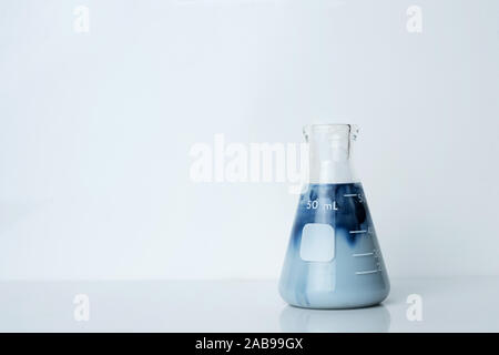 single creamy opaque blue green solution in science glass flask in chemistry laboratory background Stock Photo