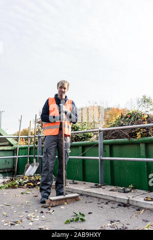 Man sweeping the floor of recycling center after delivering waste green Stock Photo