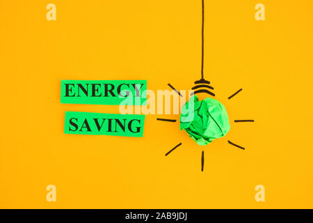 Crumpled paper light bulb and the words Energy Saving. Close up. Stock Photo