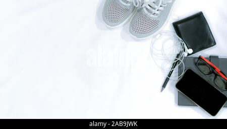 Top view of shoes, smartphone, wallet, earphone, glasses, notebook, and pencil on white desk table with copy space. Top view casual style fashion Stock Photo